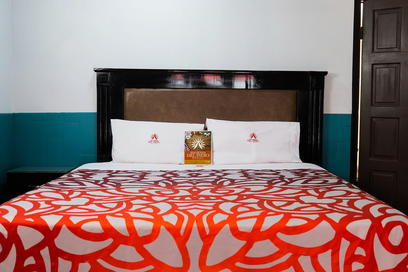 Cama matrimonial con colcha roja y blanca en la habitación sencilla