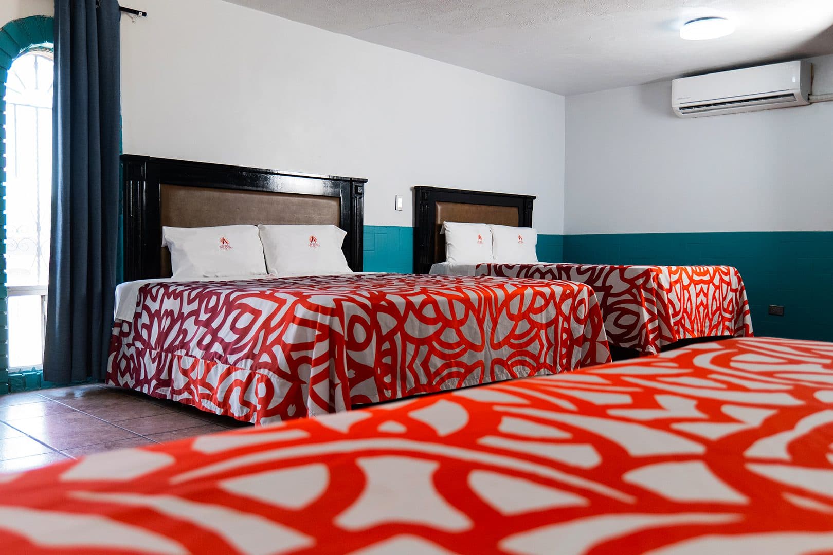 Tres camas con colchas rojas en la habitación triple con aire acondicionado