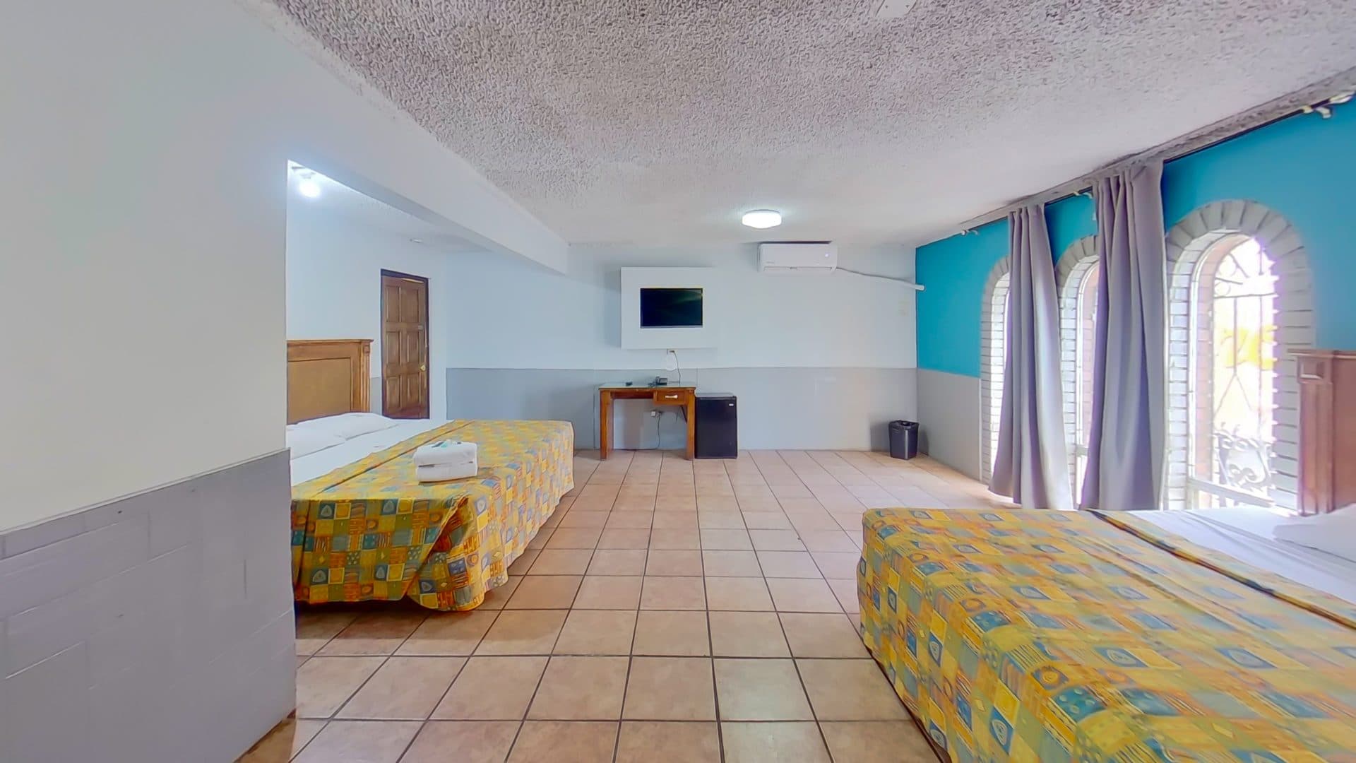 Habitación doble con escritorio, televisión y aire acondicionado